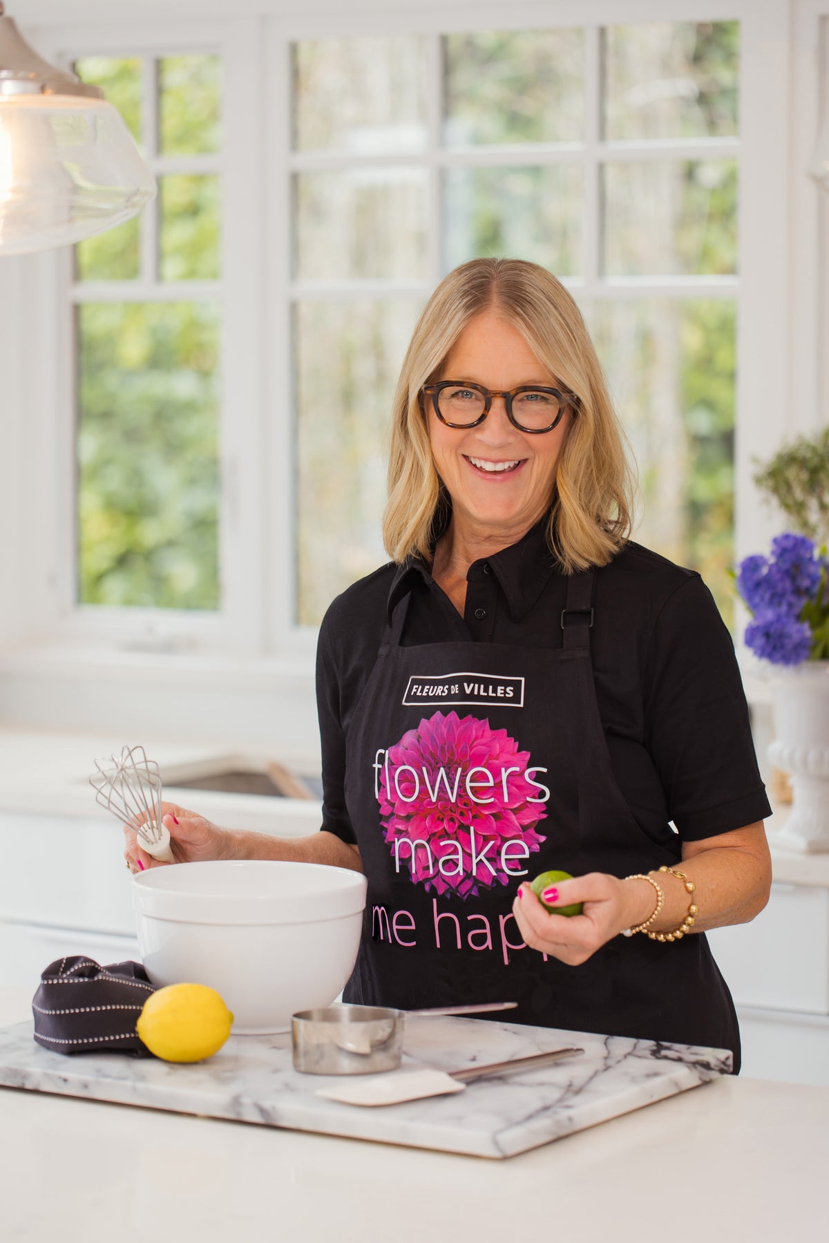 Woman in a kitchen wearing a 'Flowers Make Me Happy' apron.